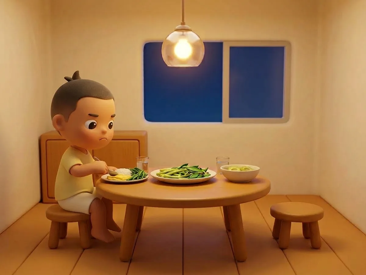 เด็กชายนั่งอยู่คนเดียวที่โต๊ะกินข้าว ก้มหน้ามองจาน ปากยื่นเล็กน้อย ใช้ช้อนเขี่ยผักบุ้งไปกองไว้ที่ริมจาน เหลือข้าวกับไข่เจียวไว้กลางจาน ม้านั่งอีกฝั่งของโต๊ะว่างอยู่และมีถ้วยซุปมะระวางอยู่ตรงนั้น